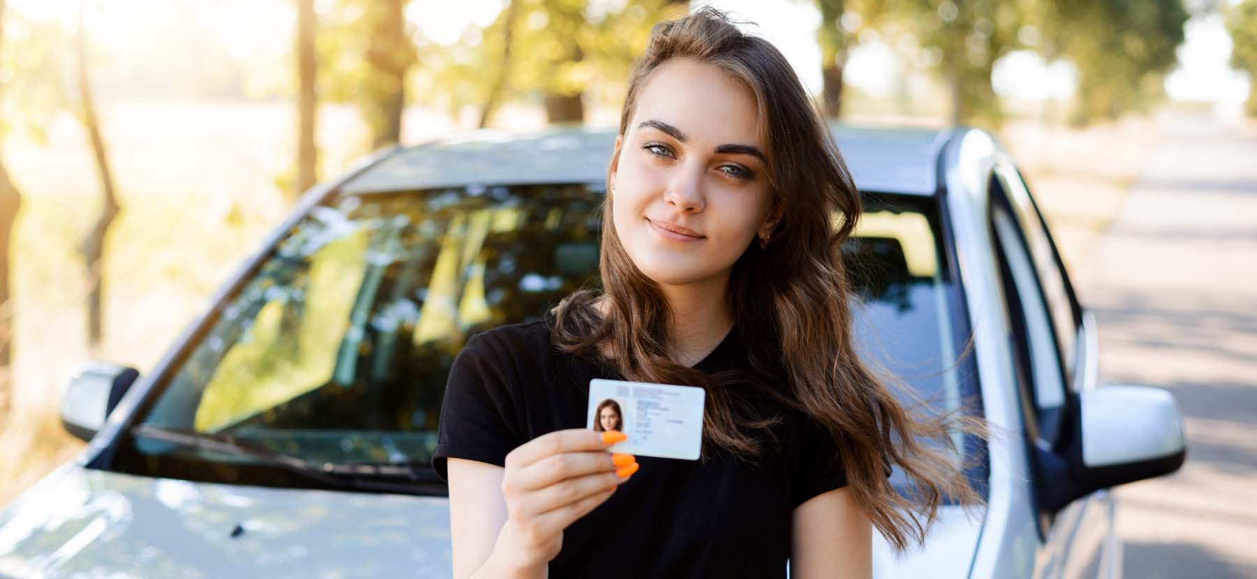 student showing driving license sitting besides her instructor in driving school Irving