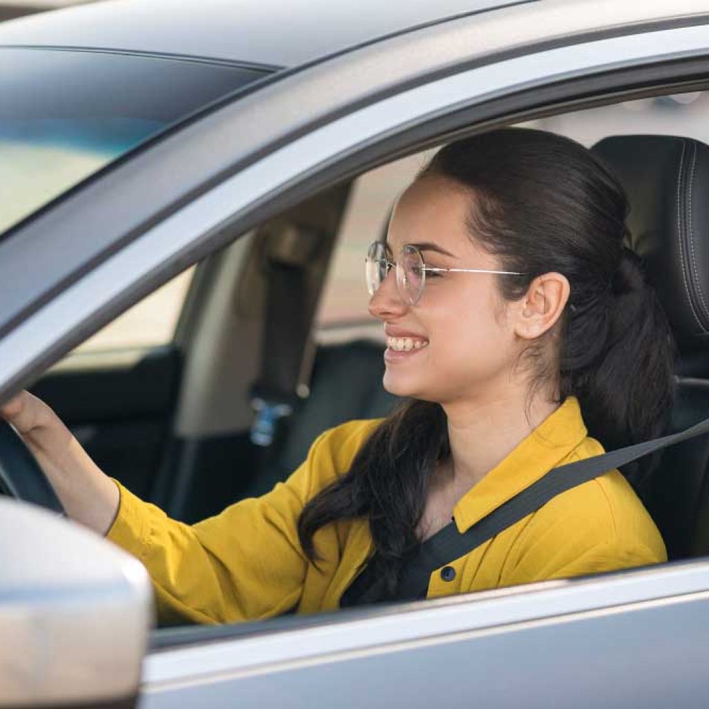 a girl is smiling and holding the wheel at our driving school in Irving Tx